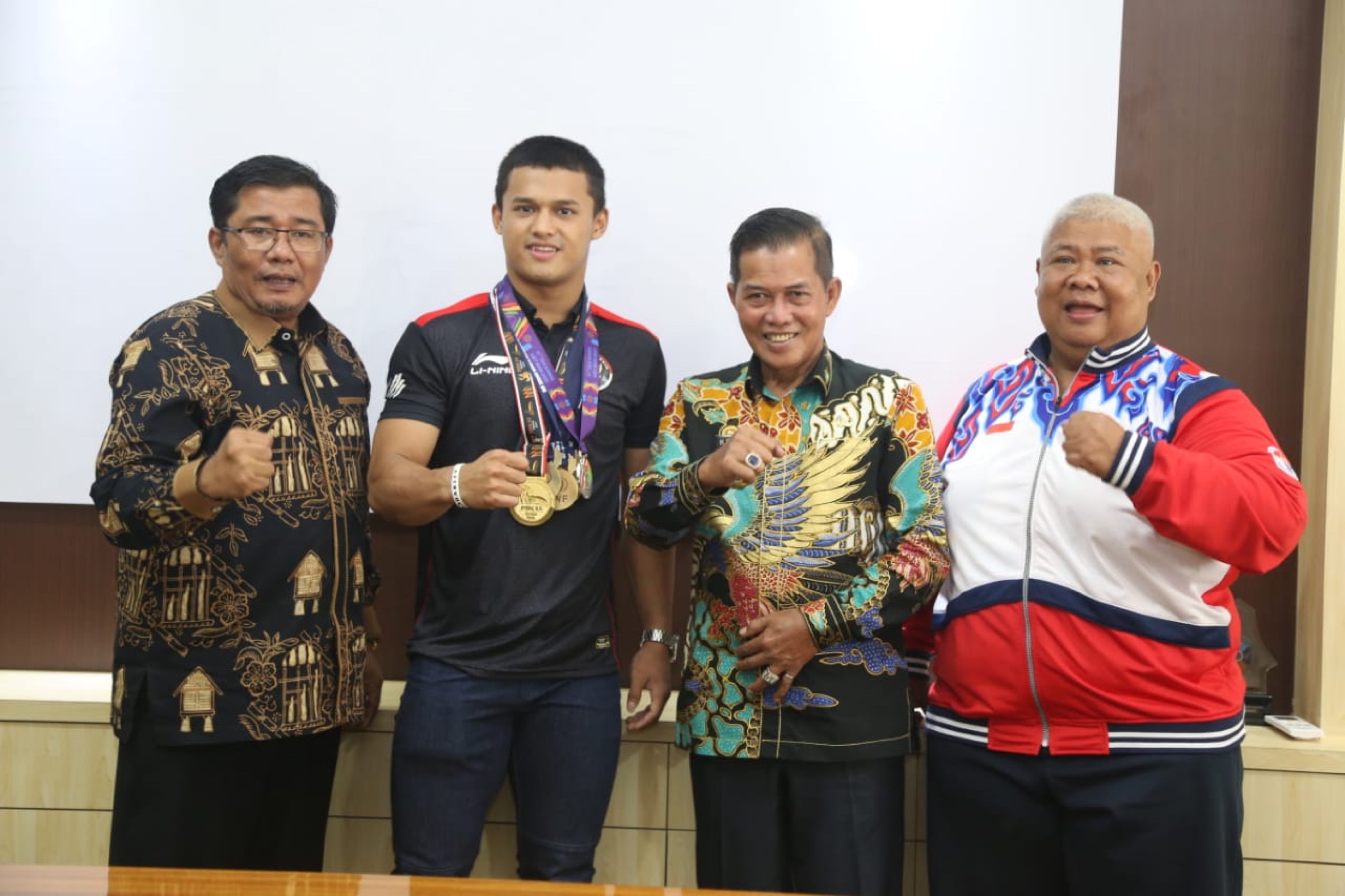 Rizki Juniansyah displaying medals with Indonesian sporting officials.