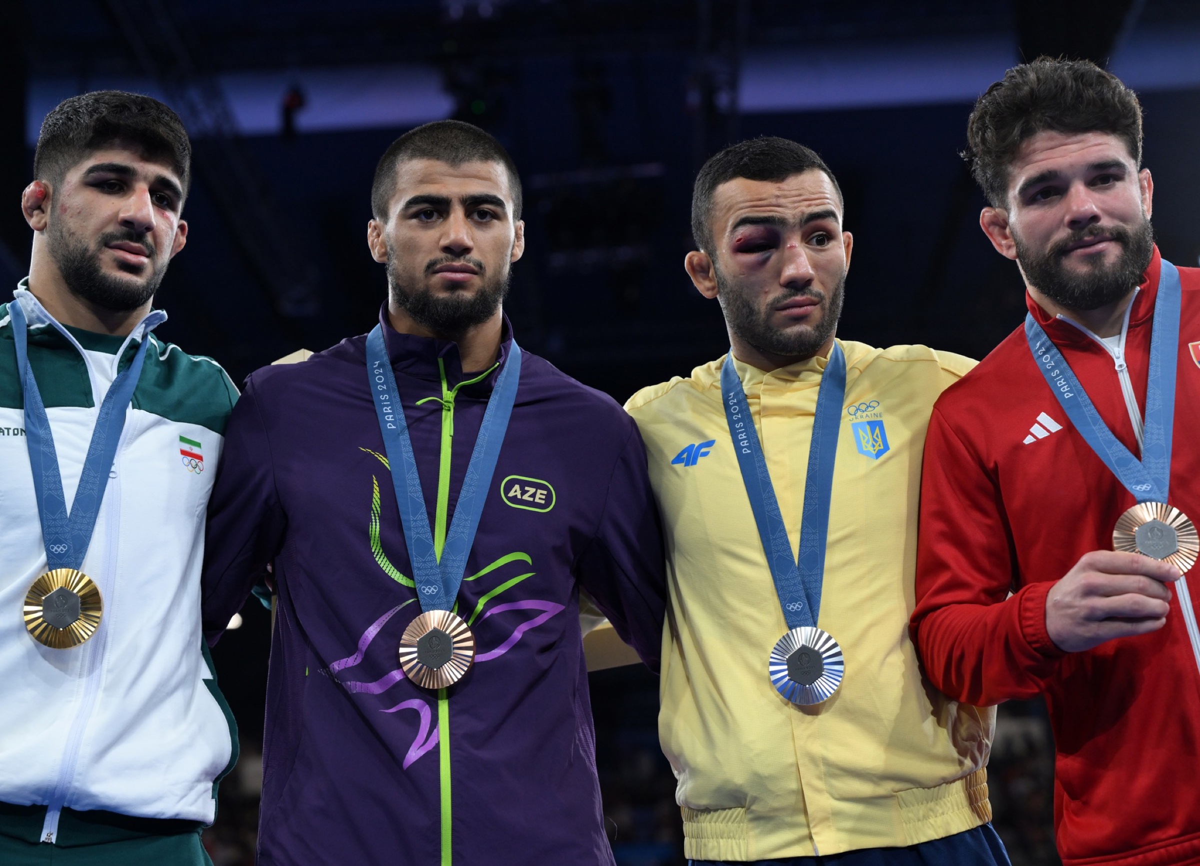 Saeid Esmaeili, left, standing with the Paris Olympic wrestling medallists.