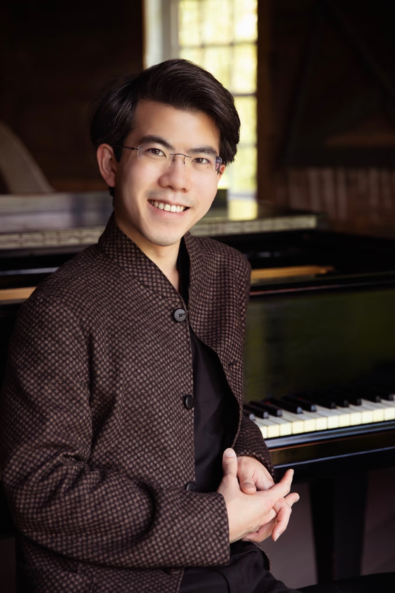 Pianist Aristo Sham seated beside a grand piano.